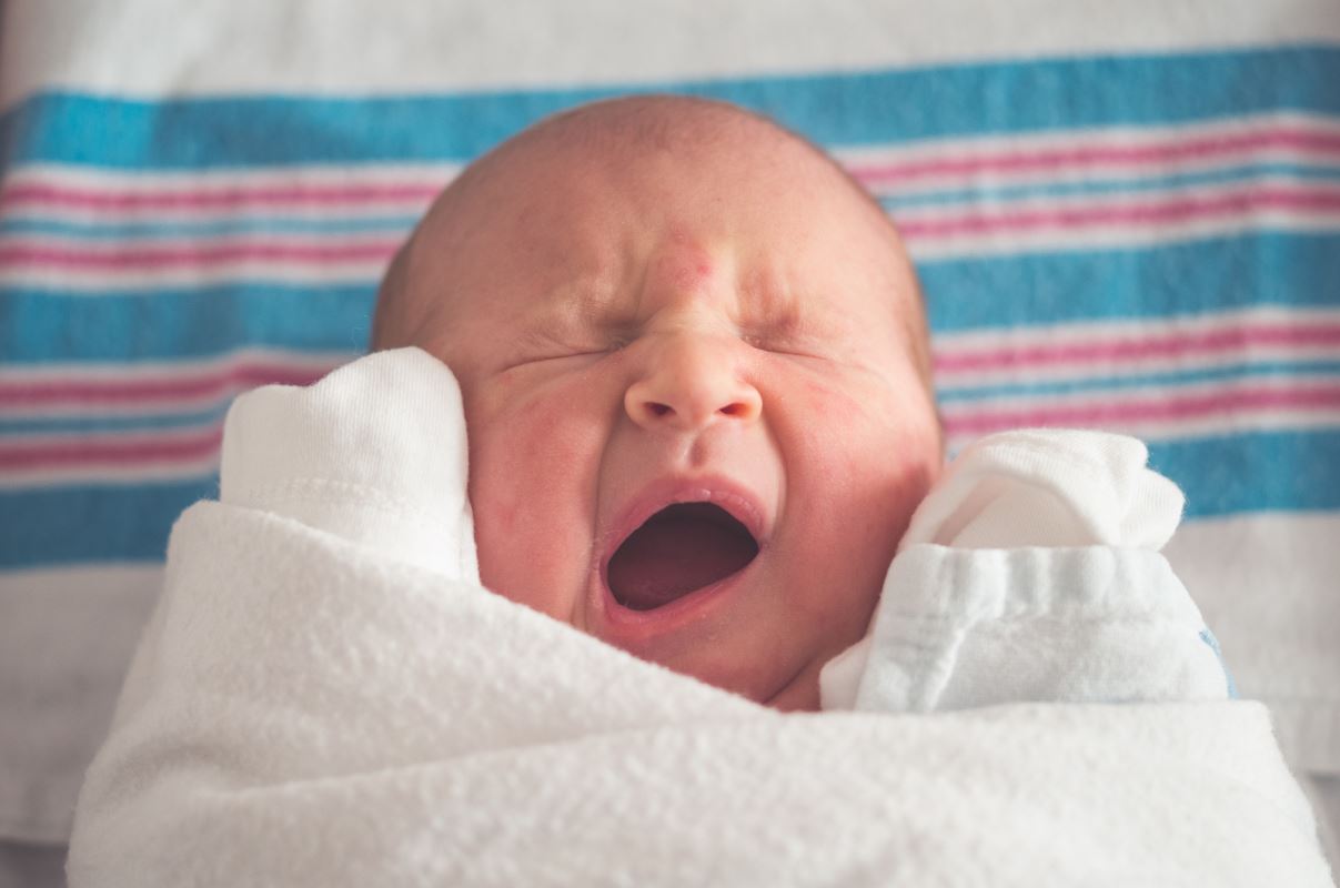 a baby yawning in a blanket