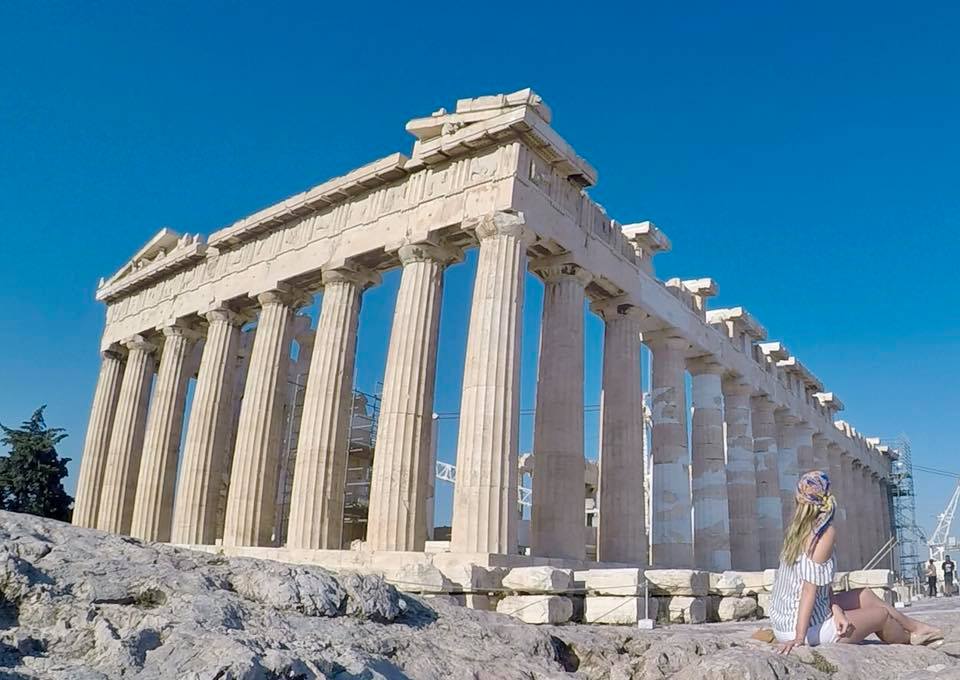 a woman sitting in front of Parthenon