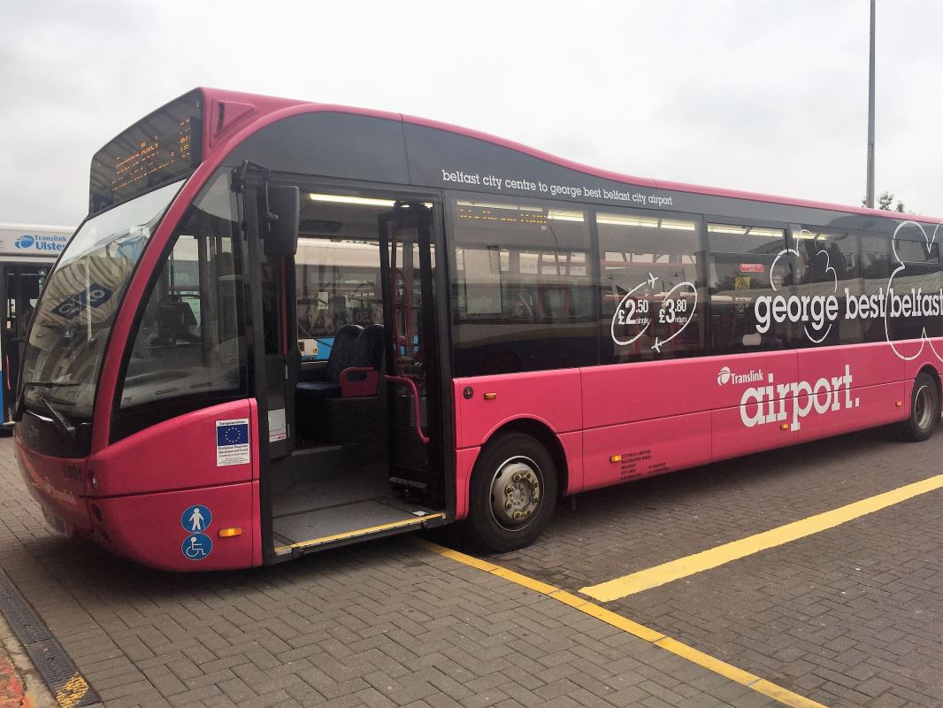 a pink bus parked on a brick road