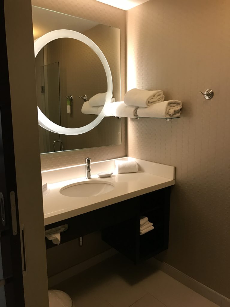 a bathroom with a round mirror and towels