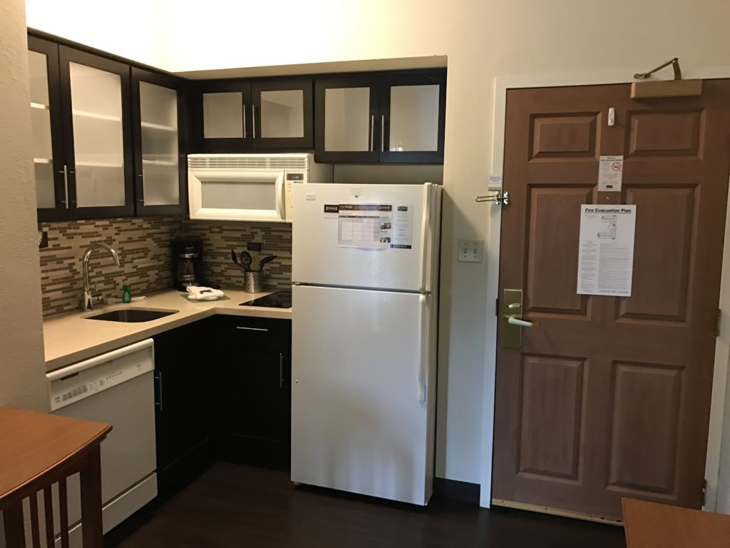 a kitchen with a white refrigerator and a brown door