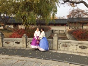 two women in traditional korean clothing standing on a bridge