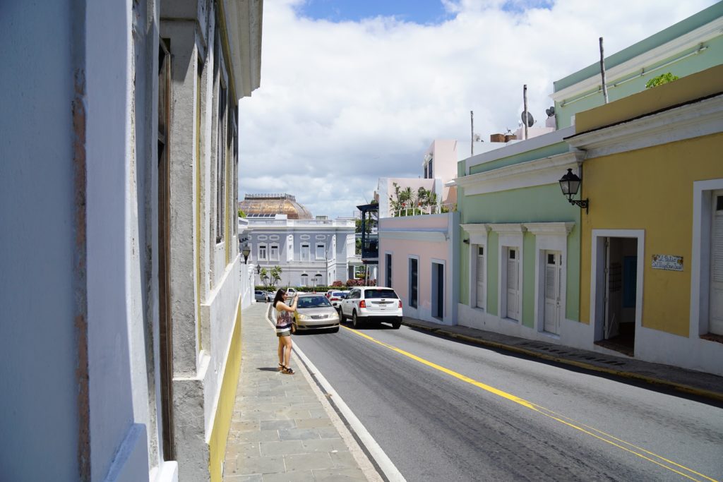 a woman standing on a sidewalk next to cars on a street