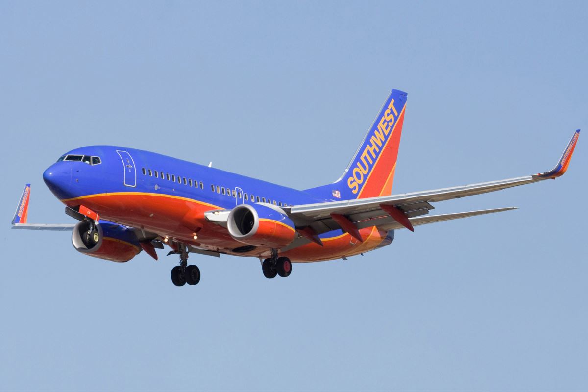 a blue and orange airplane flying in the sky