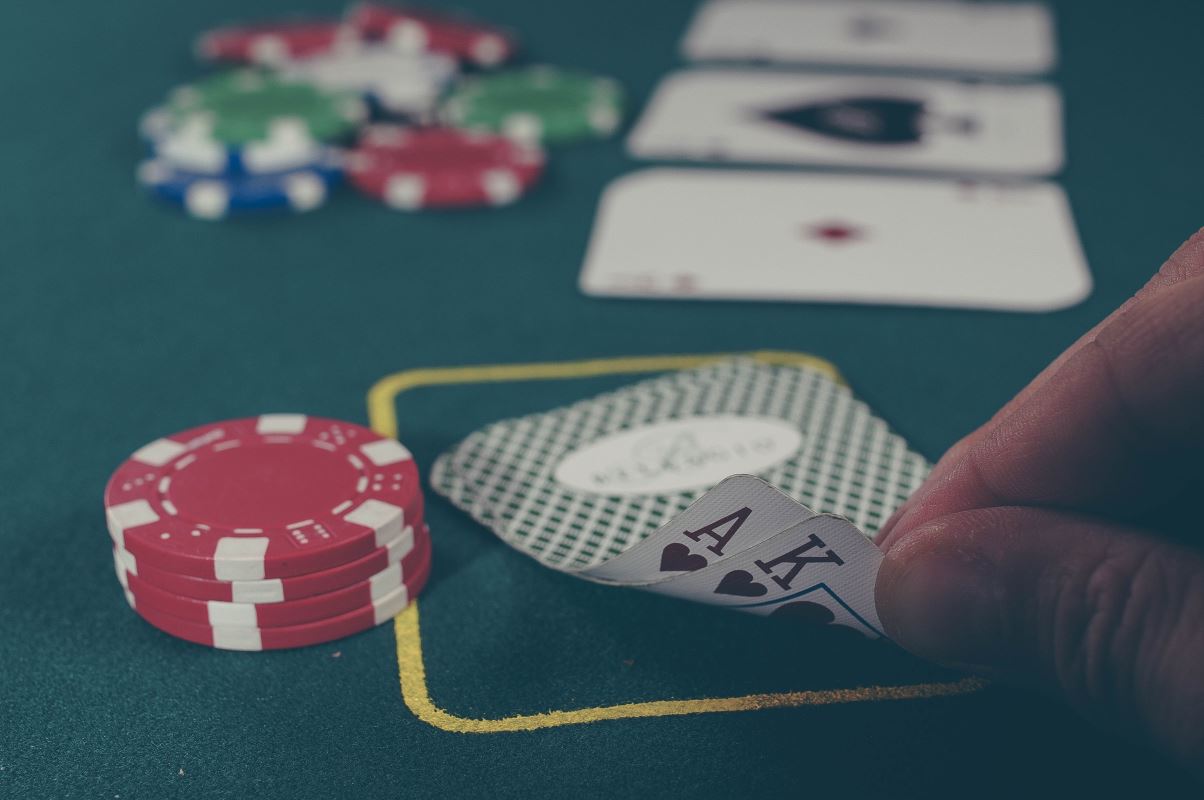 a hand holding a pair of cards and chips