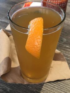 a glass of liquid with a slice of orange on top