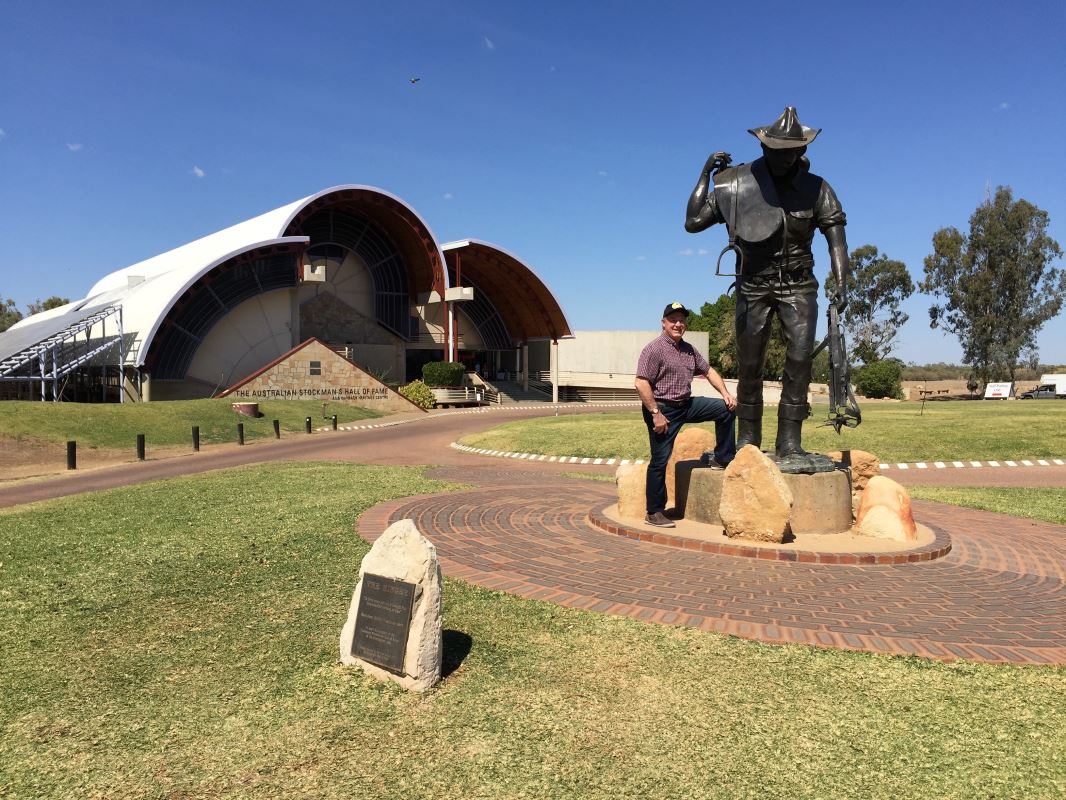 a man standing on a stone statue in front of Australian Stockman's Hall of Fame