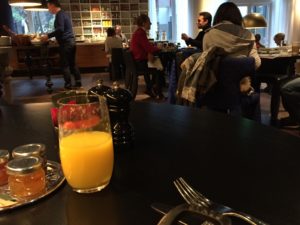 a table with a glass of orange juice and a silverware
