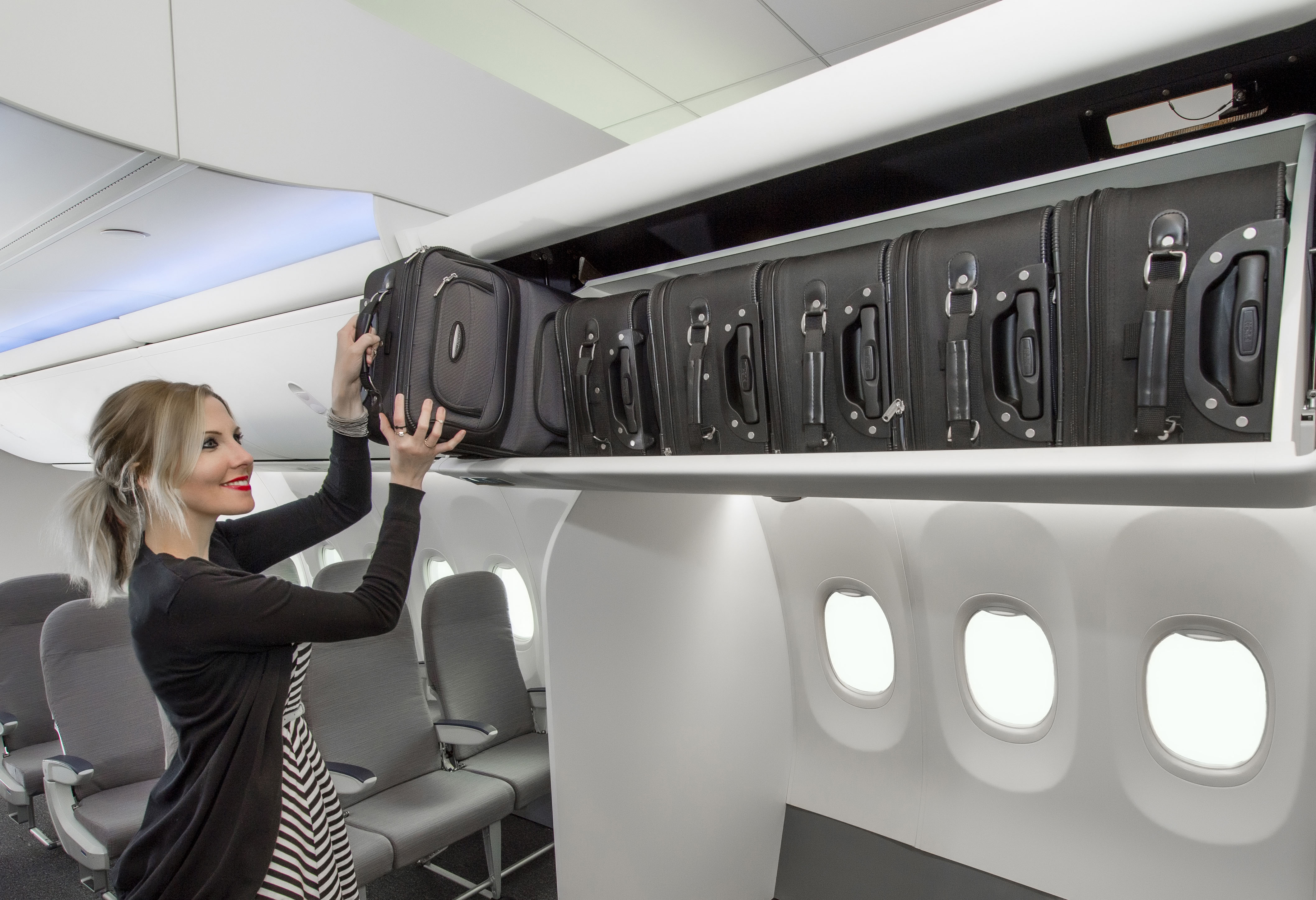 a woman putting luggage on a shelf