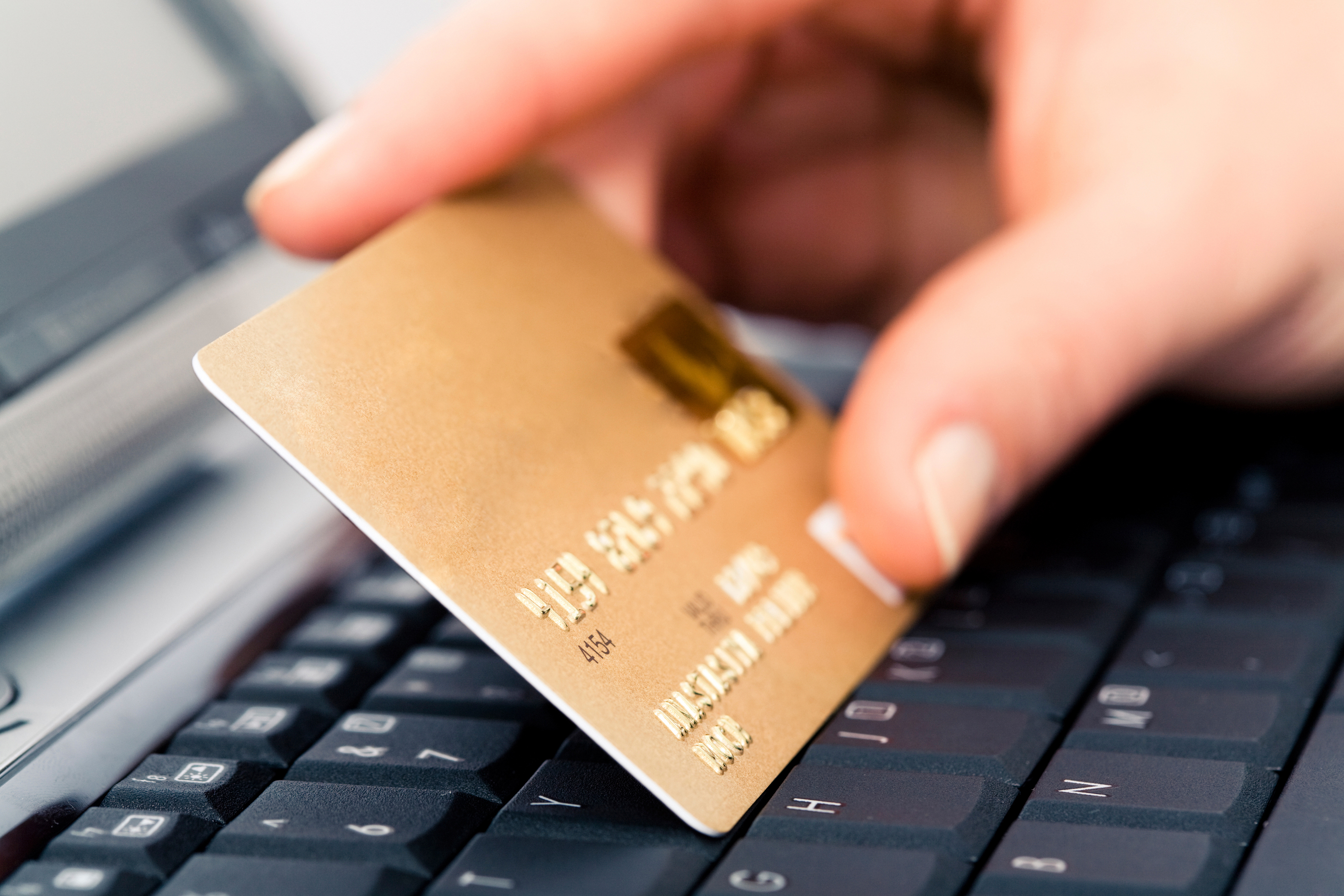 a hand holding a gold card on a keyboard