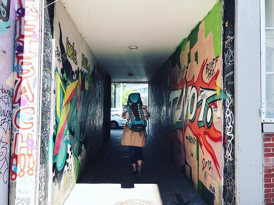 a person walking through a tunnel with graffiti