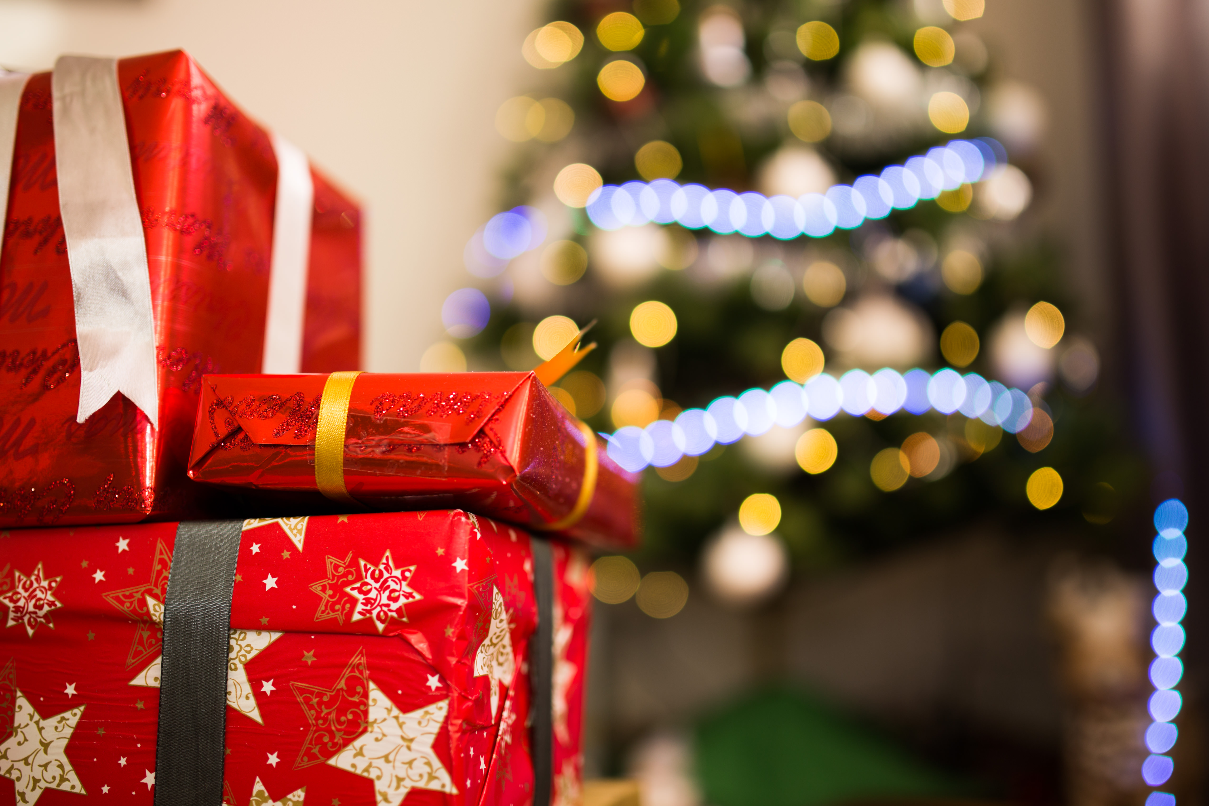 a stack of presents in front of a christmas tree