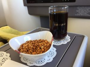 a bowl of nuts and a glass of liquid on a tray