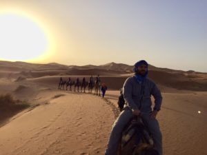 a group of people riding camels in the desert