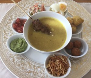 a bowl of soup with various dips on a plate