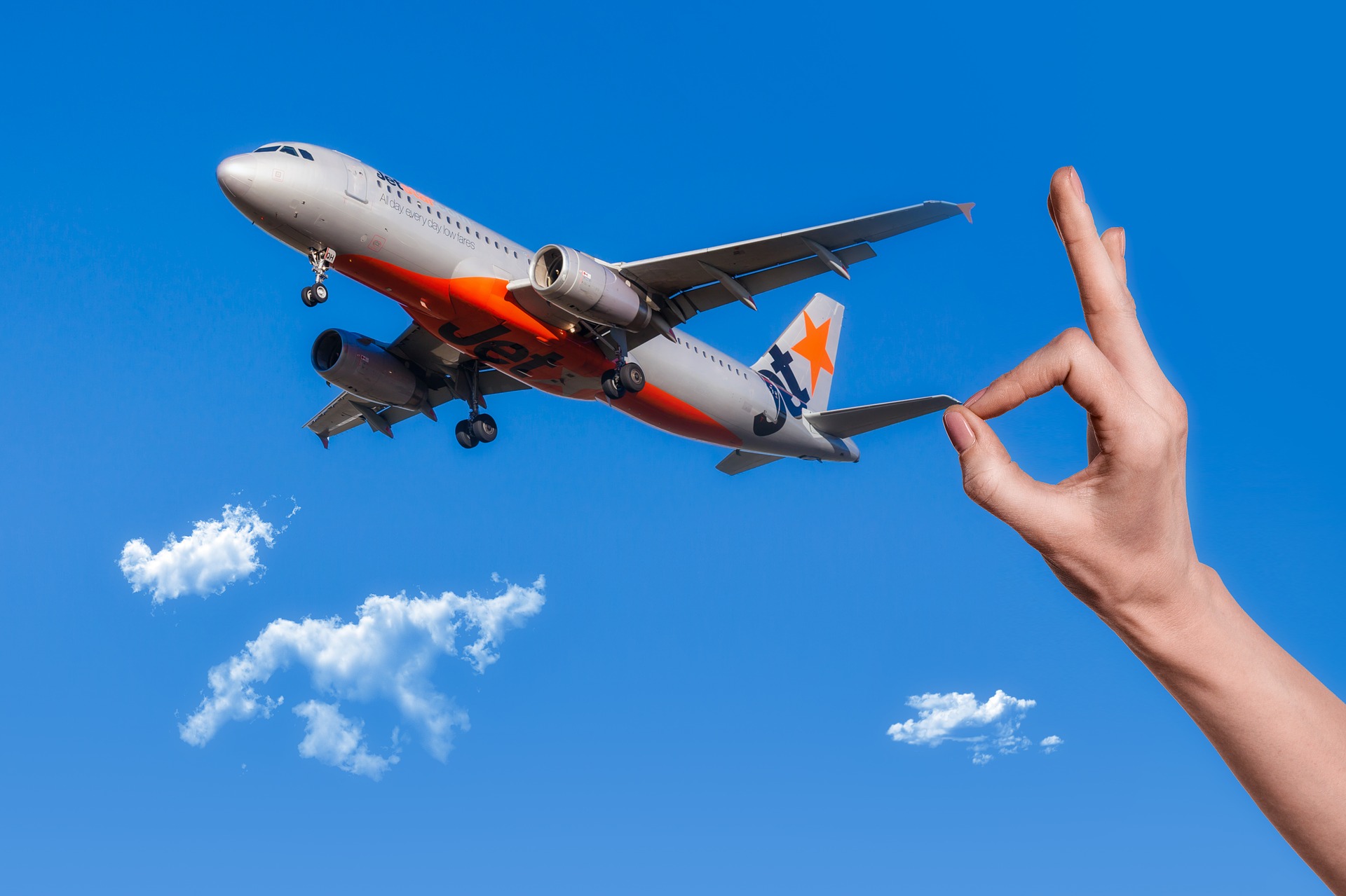 a hand pointing at an airplane in the air