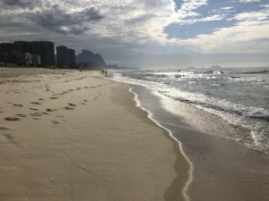 a sandy beach with water and buildings in the background