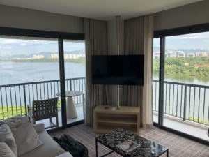 a living room with a television and a balcony overlooking a lake