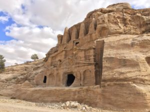 a rock structure with a hole in the side with Petra in the background