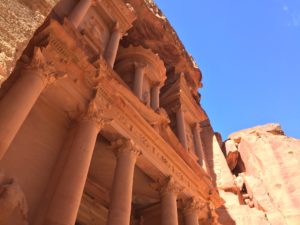 a building with pillars and a rock cliff