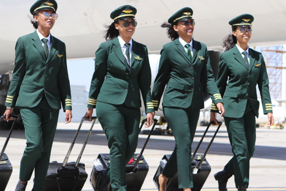 a group of women in green uniforms walking with luggage