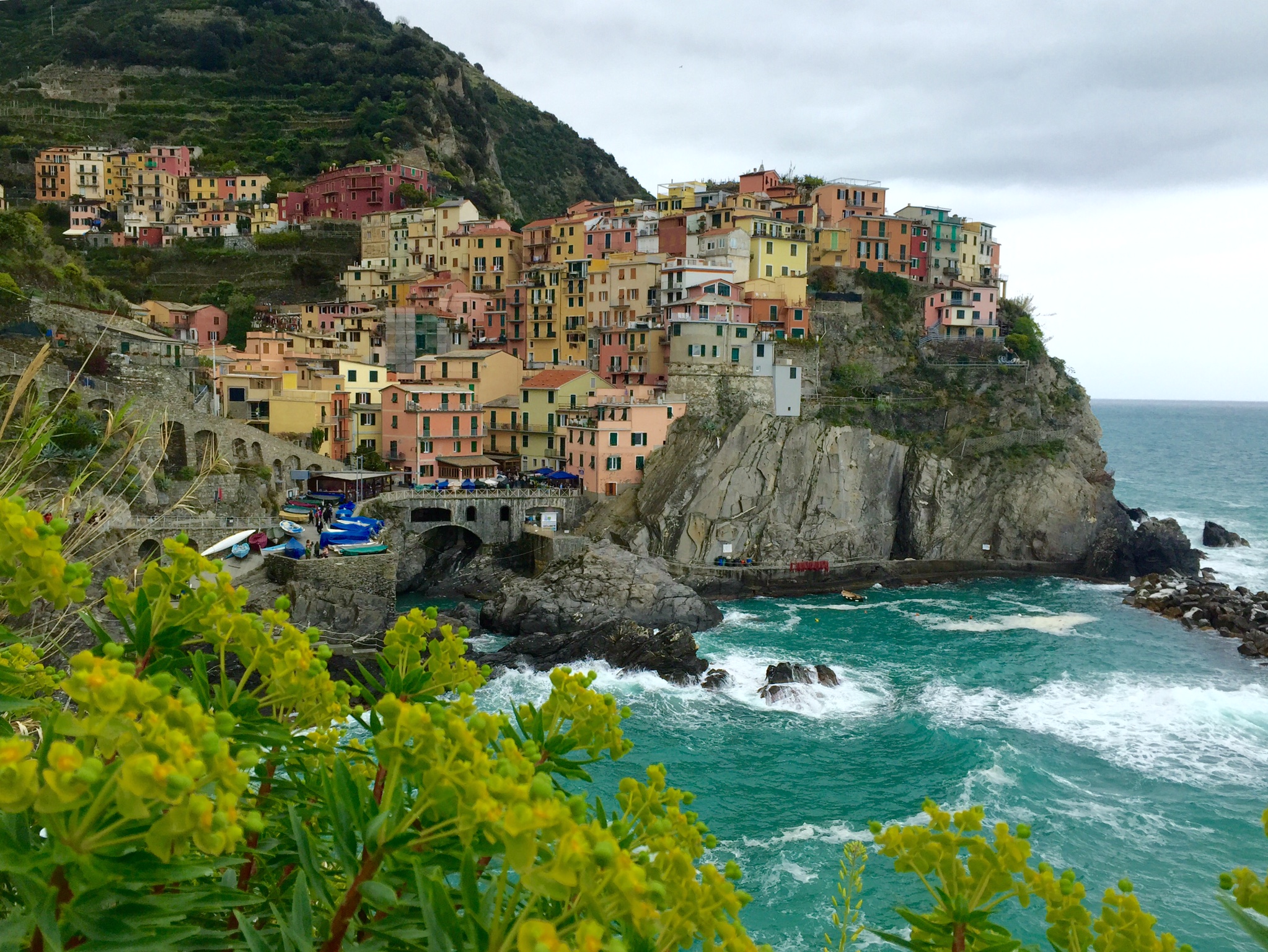 a colorful buildings on a cliff by the water with Cinque Terre in the background