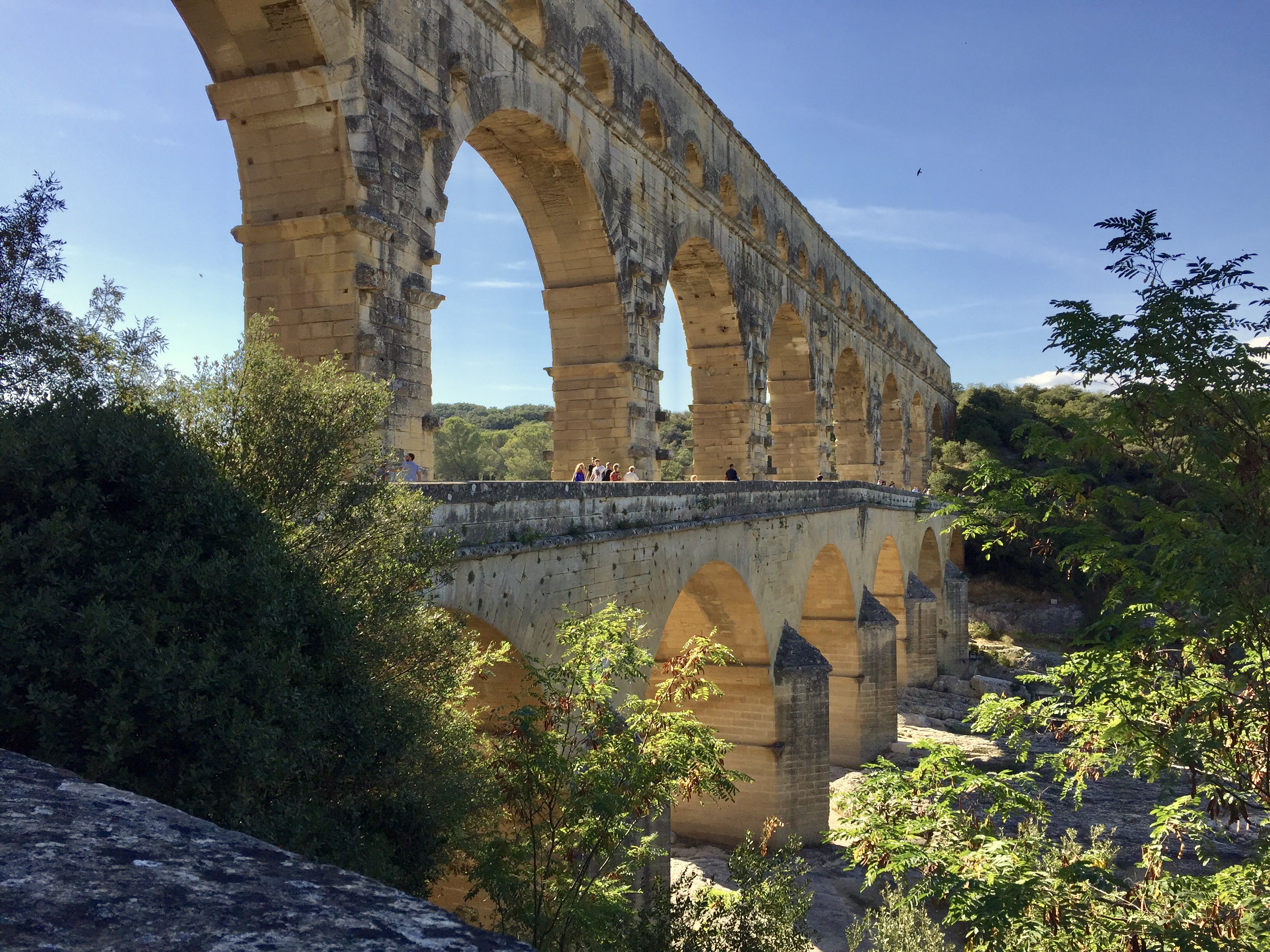 a stone bridge with arches and trees with Tarragona in the background