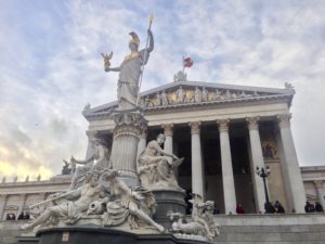 a statue of a woman holding a spear in front of a building