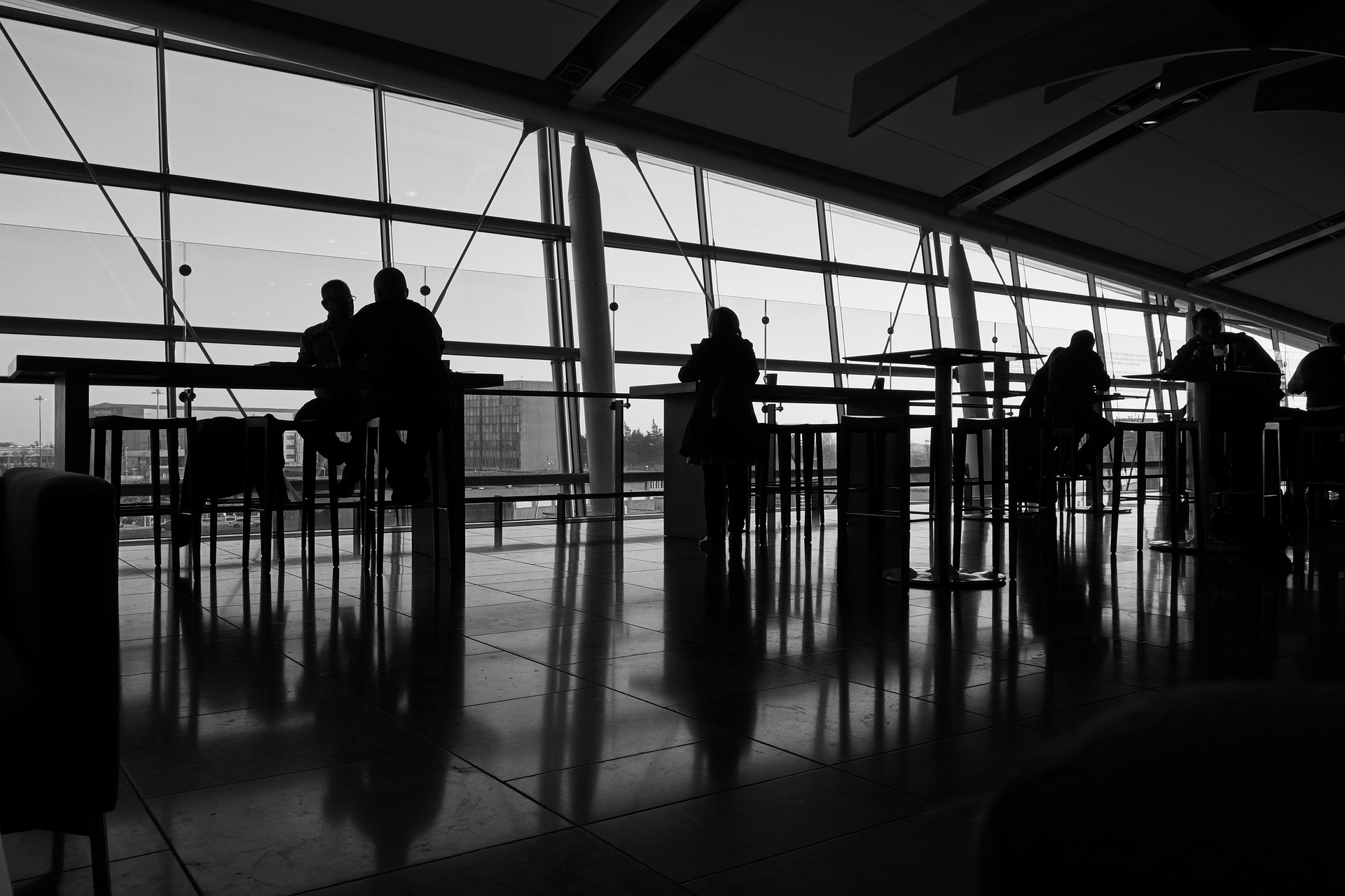 people sitting at tables in a room with large windows