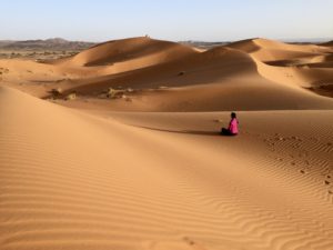 a person sitting in the middle of a desert