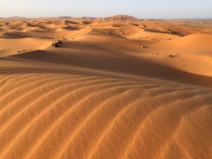 a desert with sand dunes and a vehicle