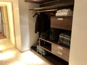 a closet with luggage and a coat on a swinger
