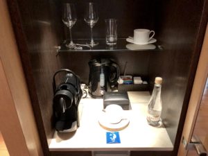 a coffee maker and wine glasses on a shelf