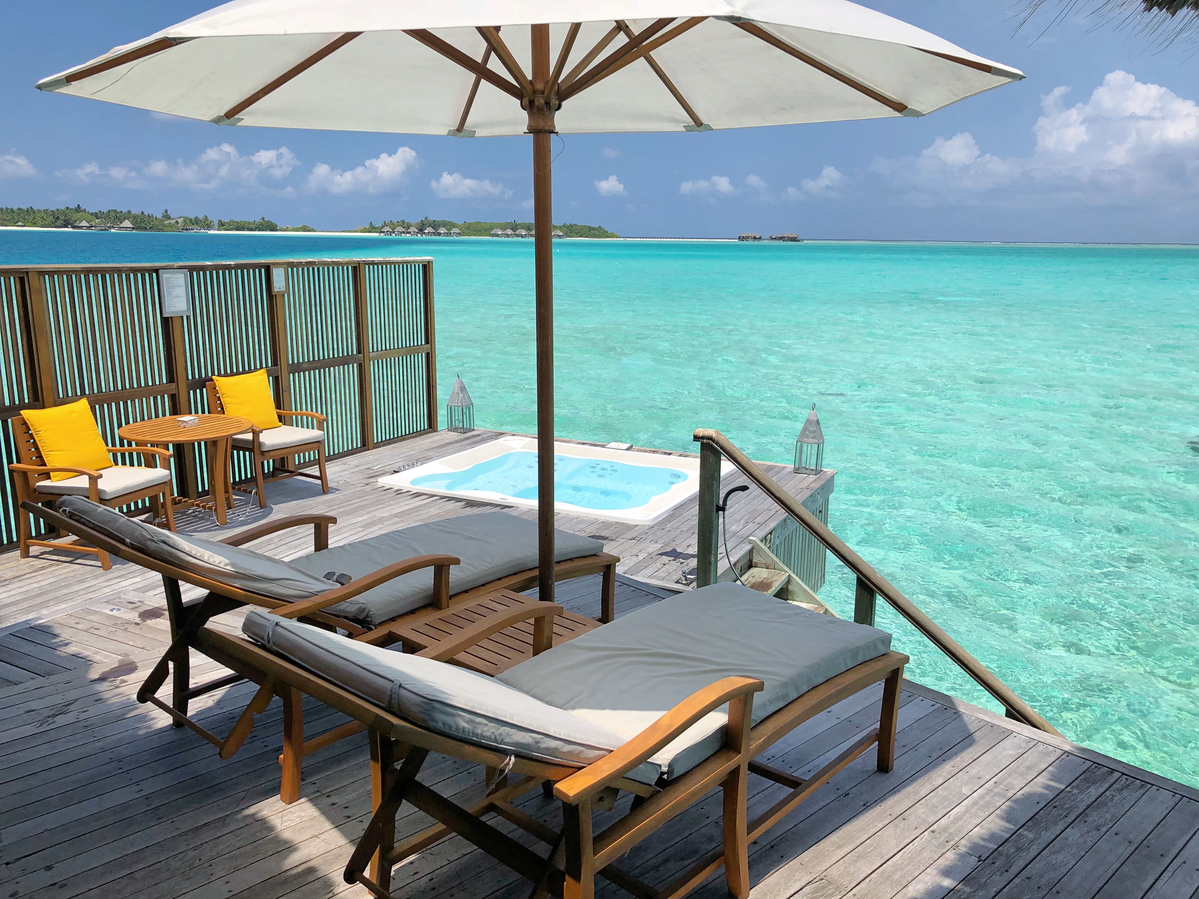 a deck with chairs and umbrella on a beach