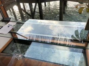 a glass table with a wooden deck and water