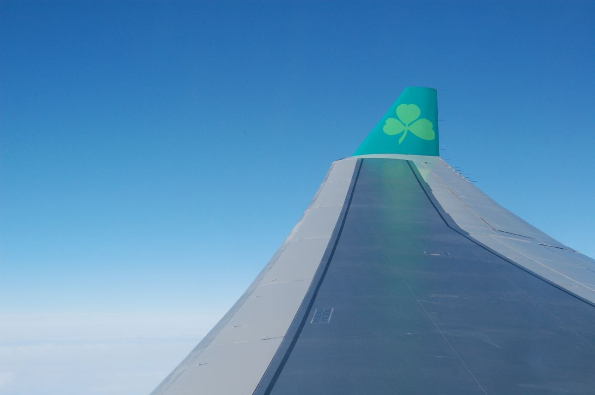 the wing of an airplane with a clover on the tail