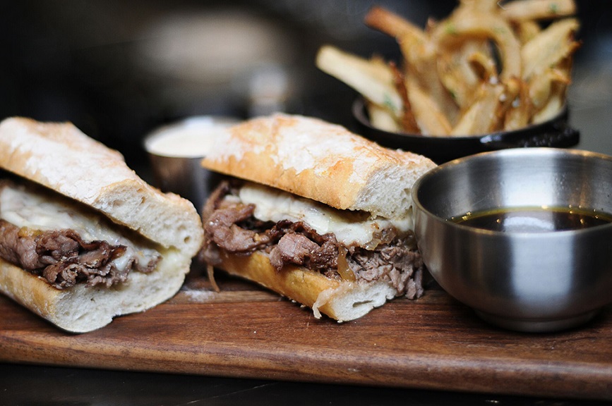 a sandwich with meat and cheese on a wooden board