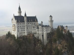 a white castle on a hill with Neuschwanstein Castle in the background