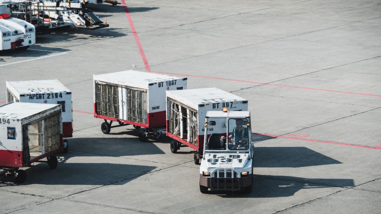 a truck and luggage carts on a tarmac