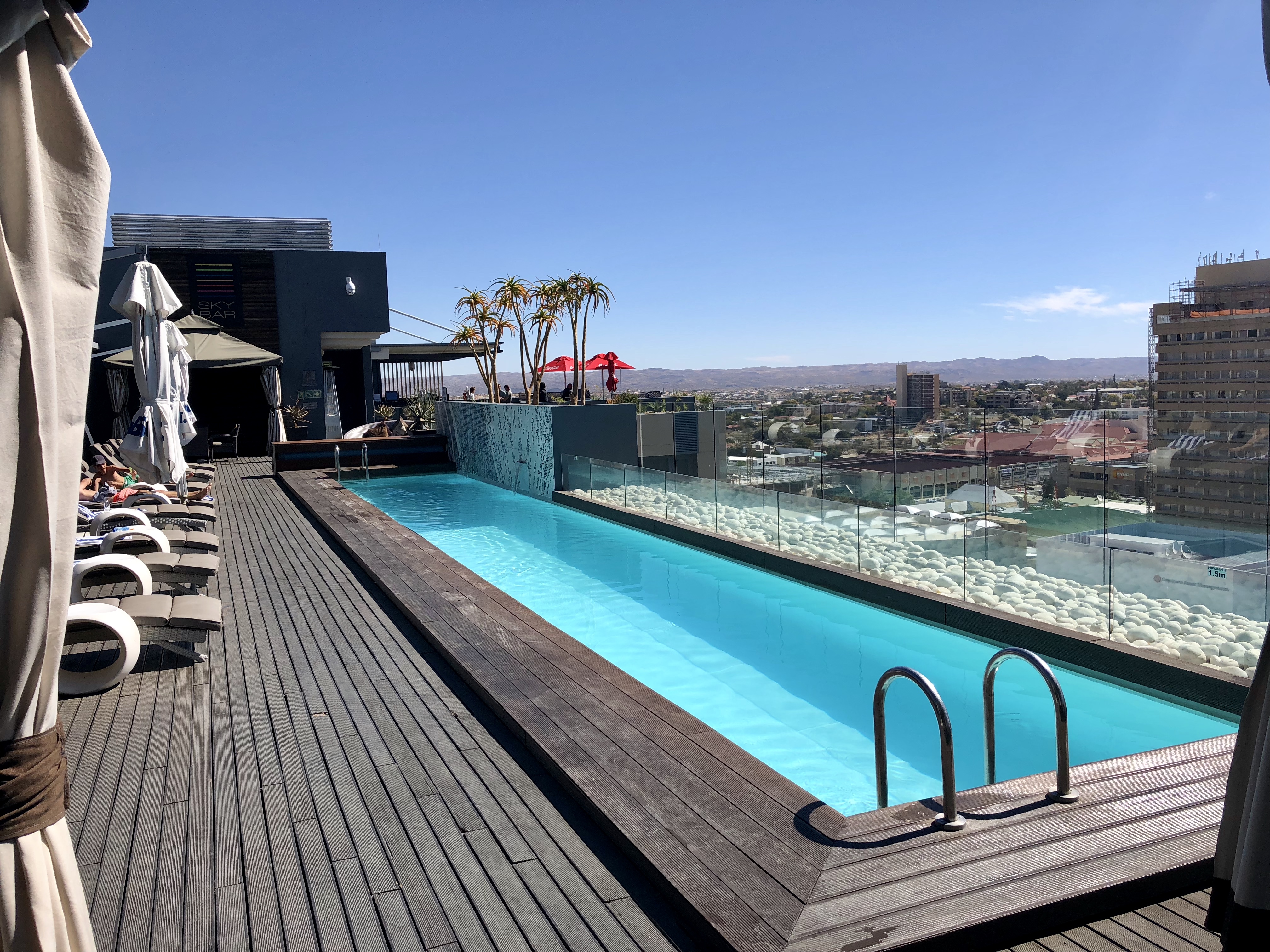 a pool on a deck with a building and a city in the background