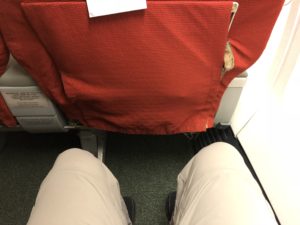 a person's legs and a red cloth on a seat