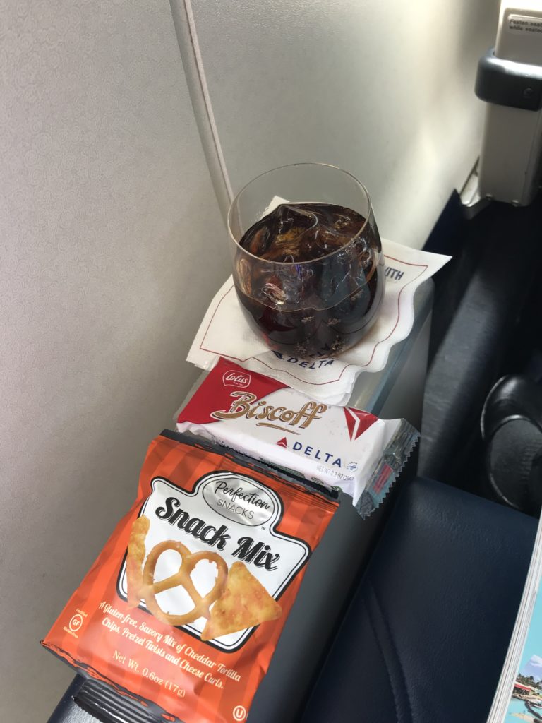 a glass of liquid and snacks on a table