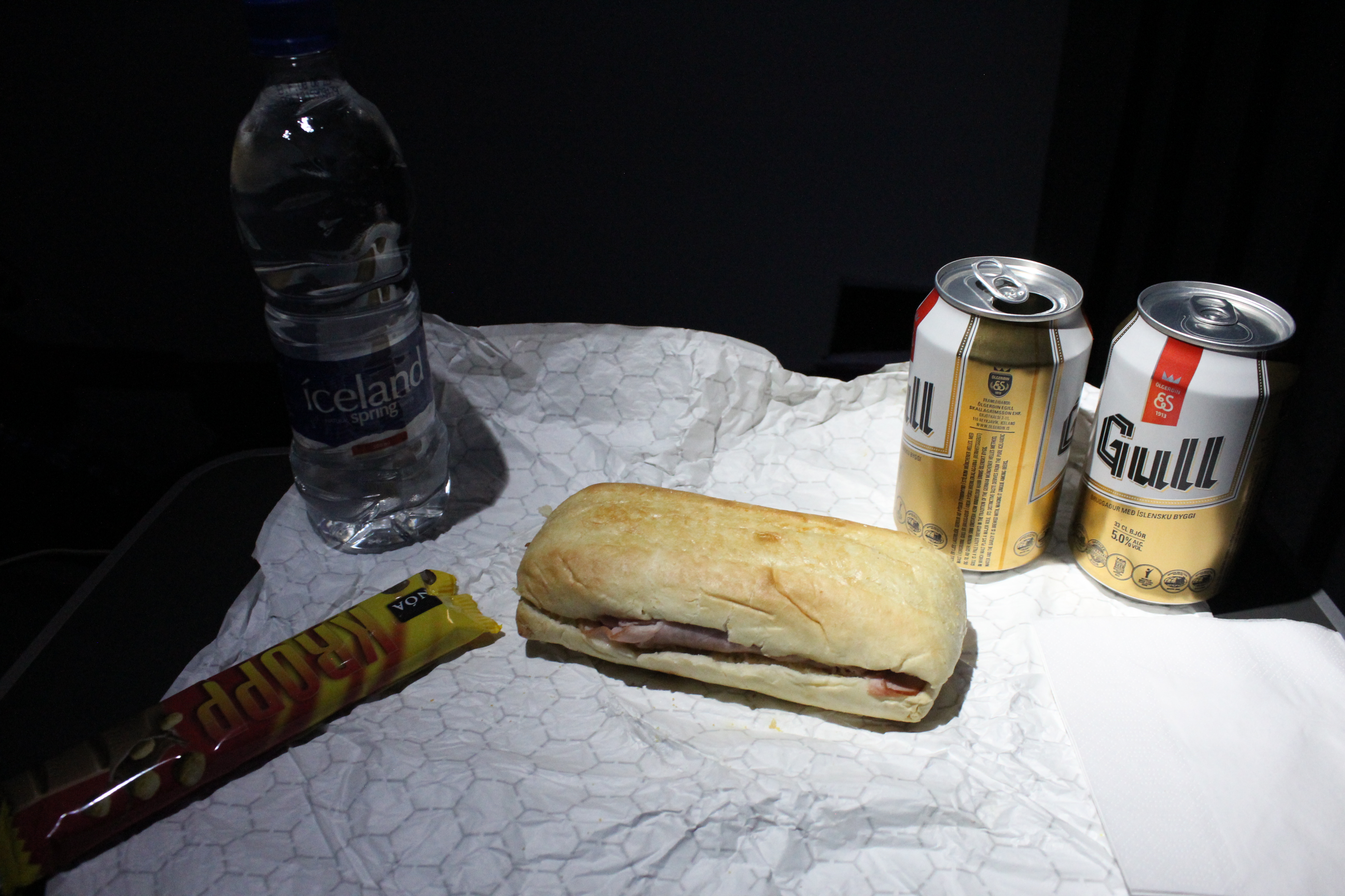 a sandwich and soda cans on a table