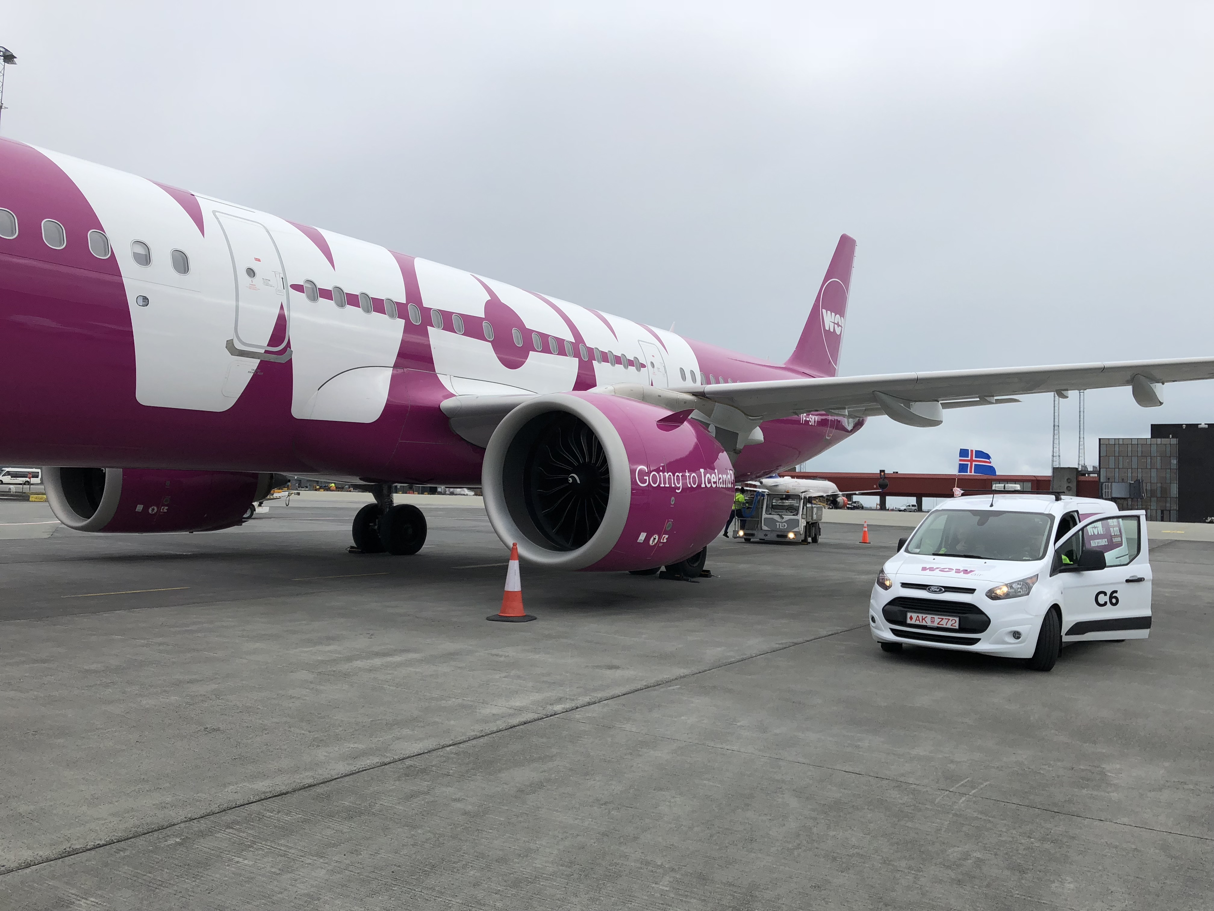 a white car next to a pink and white airplane