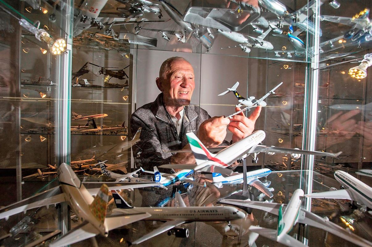 a man holding a model airplane in a glass case