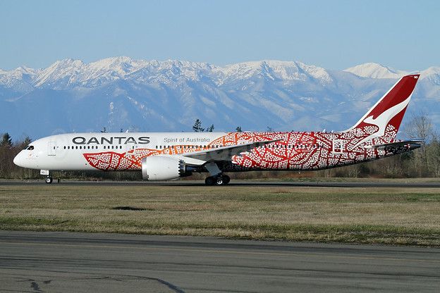 a large airplane on a runway with mountains in the background