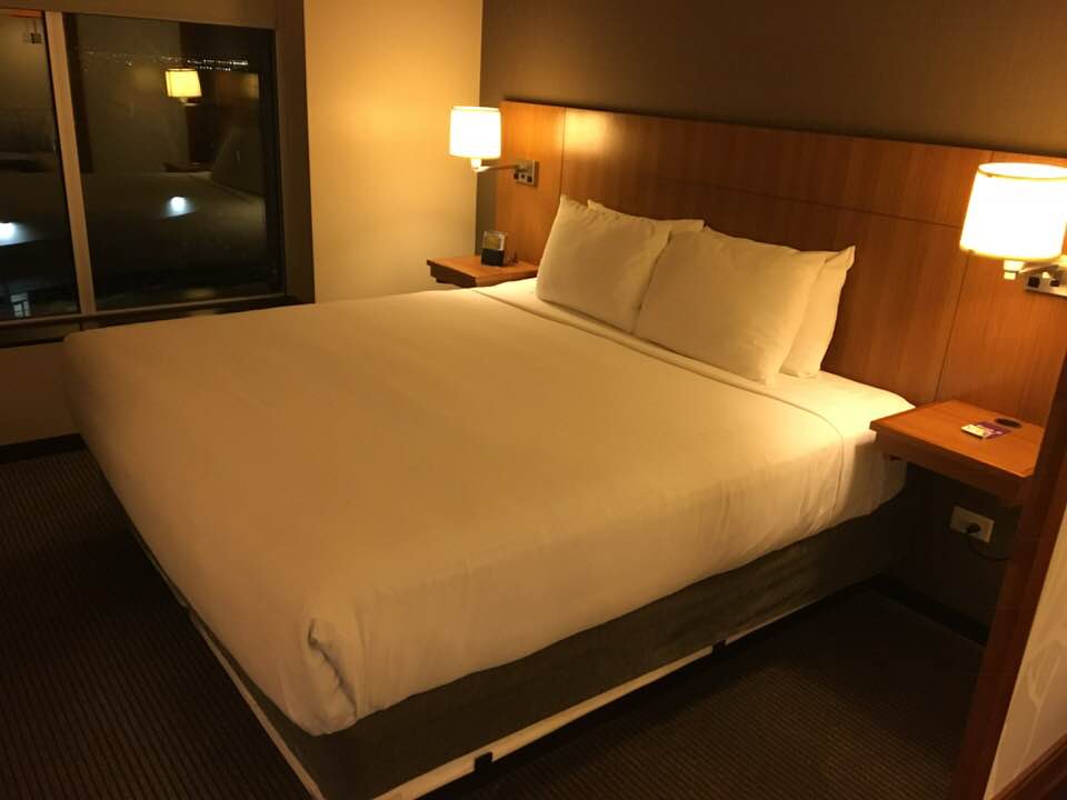 a bed with white sheets and a wood headboard