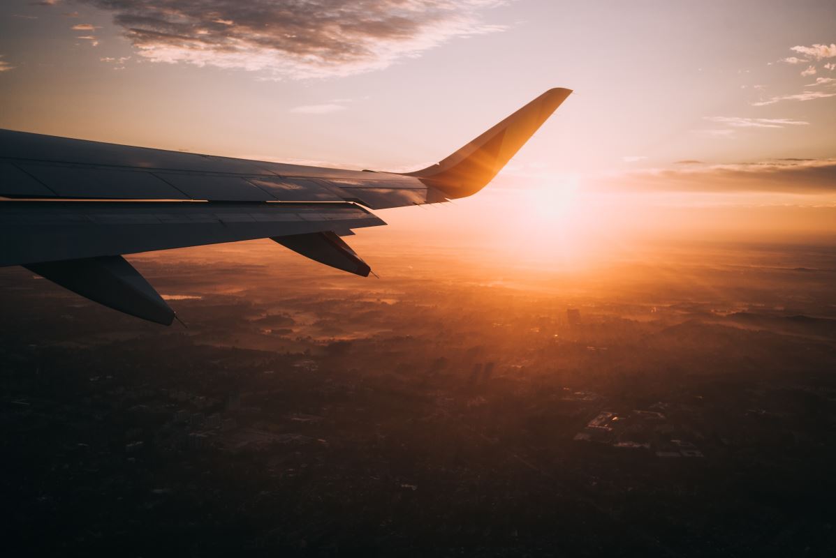 an airplane wing with the sun in the background