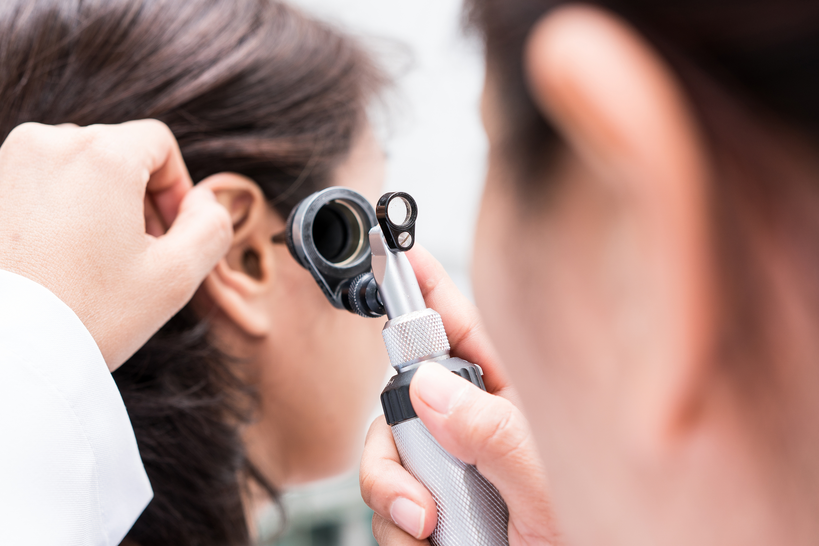 a doctor using a otoscope to check the ear