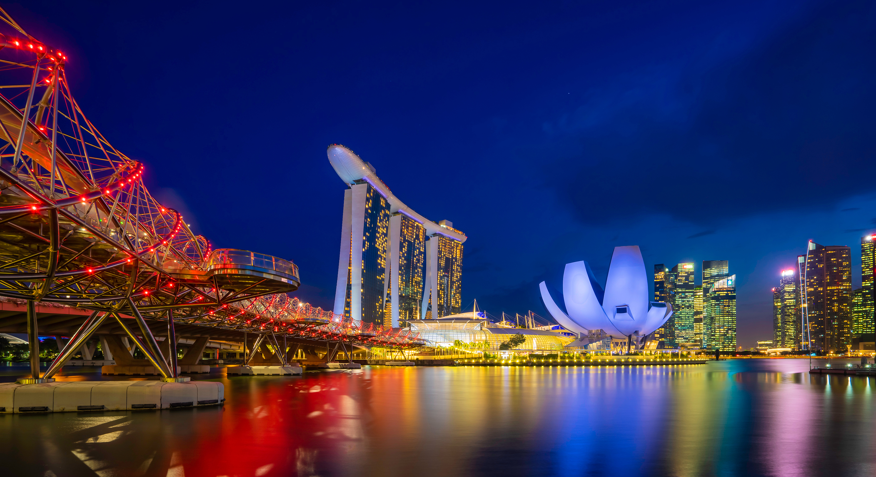 a city skyline with lights and a bridge over water